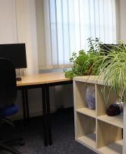 2 Arbeitsplätze mit jeweils 2 Bildschirmen und einem Bürostuhl. Dazwischen ein Regal mit mehreren Pflanzen