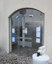 Außenansicht des Gebäudes mit gläserne Haupteingangstür und weißer Hauswand.