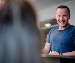 Ein fröhlicher Mann unterhält sich mit einer anderen Person und lacht herzlich.