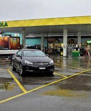AGROLA Tankstelle in Wetzikon, regnerische Aufnahme, Parkplatz im Vordergrund, Tankstelle im Hintergrund mit TopShop
