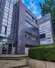 eine Gläserne Haupteingangstür, links Beschilderung WBS TRAINING AG und weitere Firmen.