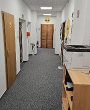 Gang mit mehreren Türen, einem Regal und einem Drucker.