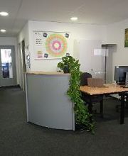 Empfangstresen mit Topfpflanze, Tisch und zwei Bildschirmen