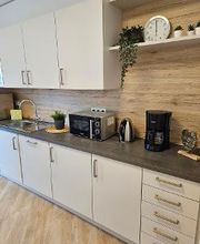 Küche mit mehreren Schränken, Wasserkocher, Kaffeemaschine, Mikrowelle und mehreren Pflanzen