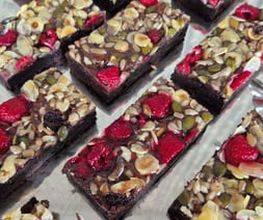 dean&david Catering | Pforzheim - Schokoladen-Brownies mit Himbeeren, Mandeln, Kürbiskernen und Sonnenblumenkernen auf Servierplatte als süßes Dessert für Buffet und Catering.