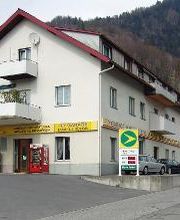 AGROLA Tankstelle in Weesen bei FLY Garage. Eine Tanksäule direkt unter Balkon gelegen. Daneben Zahlterminal und Selecta Automat. Im Vordergrund Strasse mit Einfahrt.