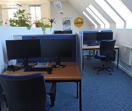 Arbeitsplätze mit zwei Bildschirmen Tastatur, Headset und MAus und dazugehöriges Lehrmaterial