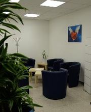 Sitzecke mit Sesseln und Pflanzen. An der Wand ein Bild von einem geflügelten Herzen.