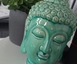 Dekoration. Buddhas Kopf aus Porzellan und eine grüne Topfpflanze.