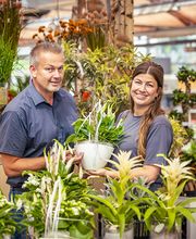 Blumen-Risse Team steht zwischen einer großen Auswahl an individuell bepflanzen Schalen im Blumenmarkt Lüdinghausen.