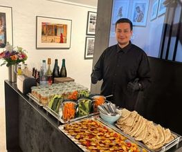 dean&david Catering | Stuttgart - Catering Station mit Gemüsesticks, Dips, Fladenbrot und Spießen, betreut von Servicepersonal für frisches Fingerfood bei Events.