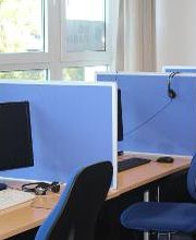 mehrere PC-Arbeitsplätze mit Trennwänden.