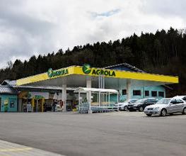 AGROLA Tankstelle in Elsau, mit TopShop, grosser Vorplatz, türkis-farbenes Gebäude hinter Tankstelle; rechts Autos geparkt