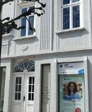 Ein weißes mehrstöckiges Haus mit einem WBS TRAINING Schild