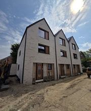 E&E Gebäudereinigung Moderne Reihenhäuser im Neubauzustand mit hellen Klinkerfassaden, großen Fenstern und sichtbaren Baustellenbereichen, die den Fortschritt der Bauarbeiten und die hochwertige Bauweise hervorheben.