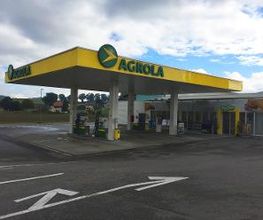 AGROLA Tankstelle in Tafers mit TopShop; links Einfahrtmarkierung mit Pfeil; Tankstelle überdacht mit mehreren Tanksäulen und Pfeilern; Himmel bewölkt