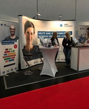 WBS-TRAINING Messestand mit Plakataufstellern und 2 Beraterinnen an einem Stehtisch.