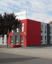 Außenansicht eines rot-grauen Gebäudes, Schild "Office-Point" auf dem Gebäude, im Vordergrund Parkplatz