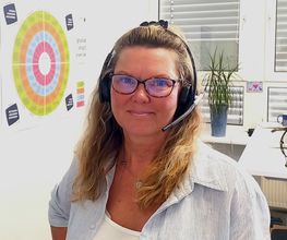 Eine Frau mit Brille und langen blonden Haaren. Sie trägt ein Headset auf dem Kopf.