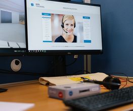 Arbeitsplatz mit zwei Bildschirmen, Tastatur und Kopfhörer