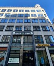 Außenansicht des Einganges zum WBS TRAINING Gebäude. Auf der Fassade sind mehrere Banner und Schilder von bekannten Unternehmen angebracht.