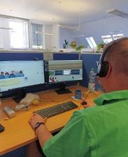 Teilnehmer sitzt am Arbeitsplatz und lernt in der virtuellen lernumgebung und hört mit Headset dem Unterricht zu