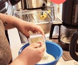 Eine Teilnehmerin beim Backen am Standort. Schüssel mit Mehl. Darüber ein Herz mit einem lächelnden Gesicht.