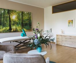 Großzügiger Behandlungsraum von Physiotherapie Birkhoff mit Therapieliege, Sitzbereich, Pflanzen und hellem Ambiente. Das Bild passt zu Manueller Therapie Magdeburg, Massage Magdeburg, Fango Magdeburg und individueller Physiotherapie.